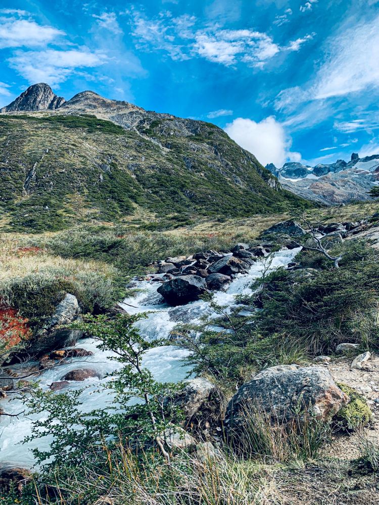 Arroyo de montaña en el valle camino a Laguna Esmeralda, con cumbres de la Cordillera de los Andes