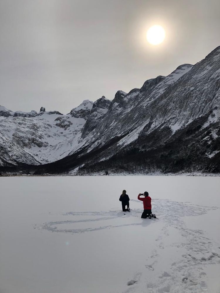 Personas sobre Laguna Esmeralda completamente congelada en invierno, rodeada de montañas nevadas